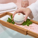 Hand placing eucalyptus bath bomb in relaxing bath soak